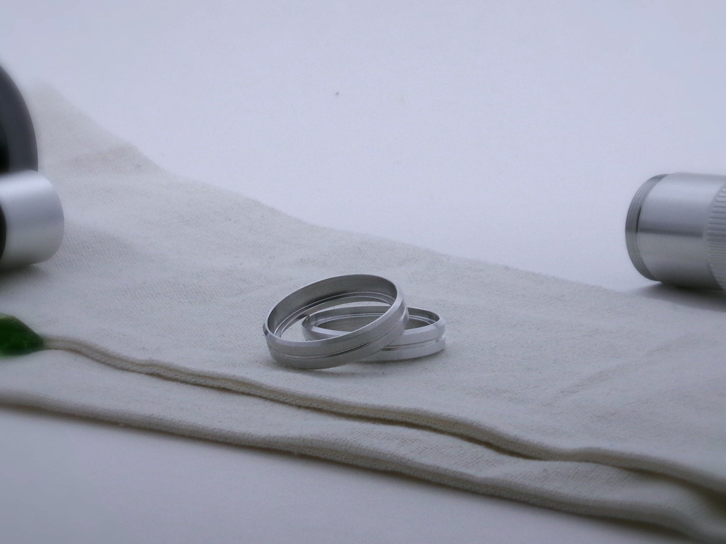 Pair of simple aluminum accent rings, with beveled edges and a central groove for VHC lightsabers, one askew upon the other, showing shimsert.