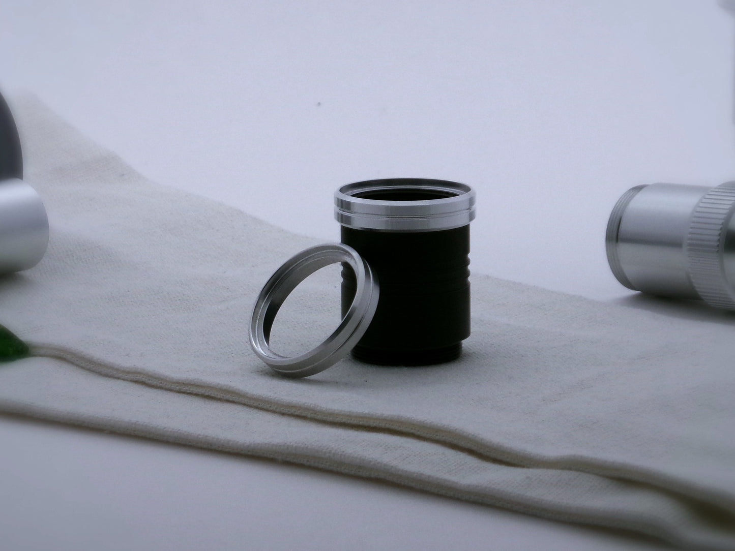 A pair of aluminum accent rings with beveled edges and a central groove for VHC lightsabers, the first installed on a black grip extension, the second leaning against it.