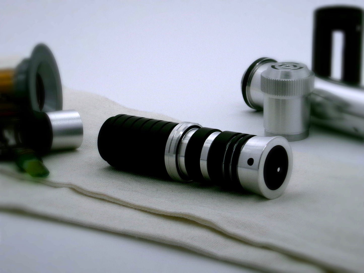 A single, aluminum accent ring with beveled edges and a central groove installed between a mixed finish emitter and black extension of a VHC lightsaber.