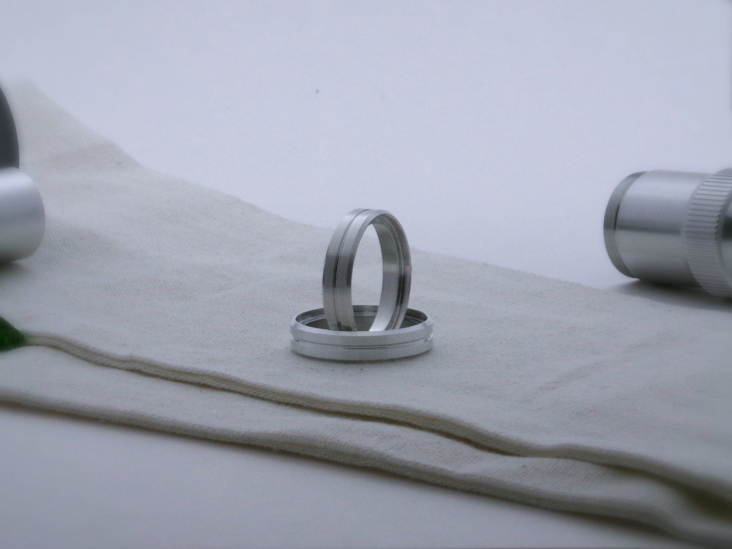 A pair of aluminum accent rings with beveled edges and a central groove for VHC lightsabers; one resting vertical inside the other.