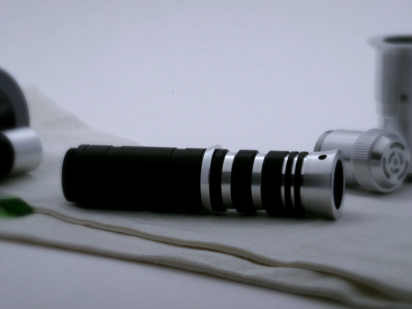 A single, beveled aluminum accent ring installed between a mixed finish emitter and black extension of a VHC lightsaber.