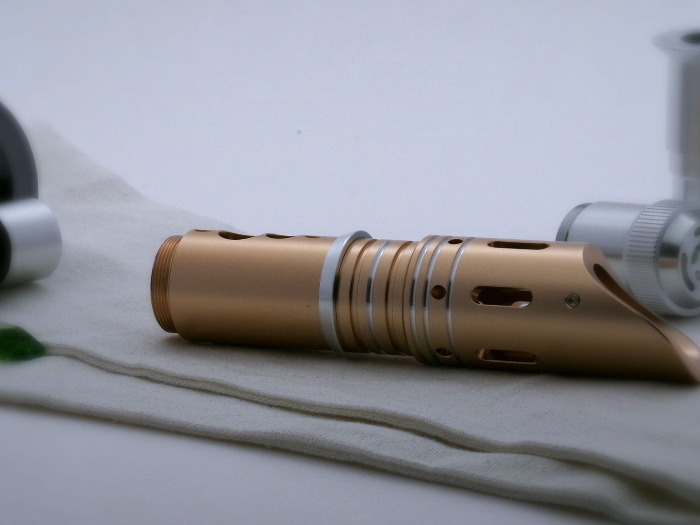 Single, beveled aluminum accent ring installed between the switch and emitter of a golden VHC lightsaber.