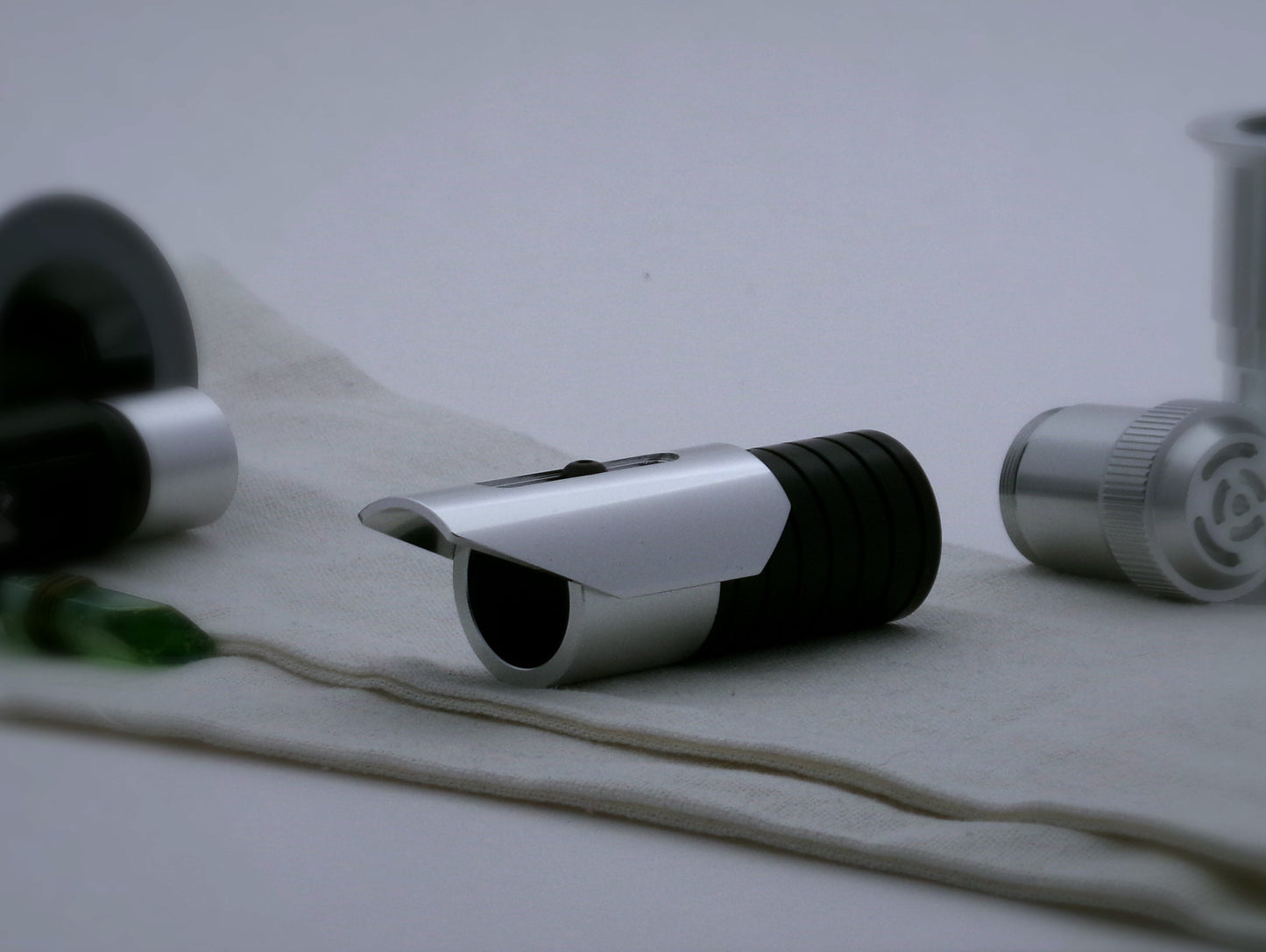 Small shield shaped, aluminum half shroud for VHC lightsabers with angled ends mounted by universal slot to an emitter mock-up; three-quarter view