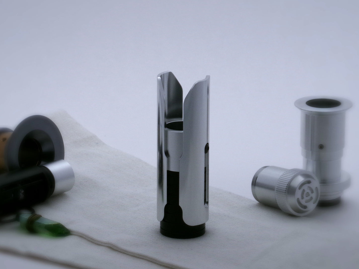 Pair of aluminum half shrouds for VHC lightsabers of Kestis design mounted by universal slot to an emitter mock-up; vertical oriented lateral view.