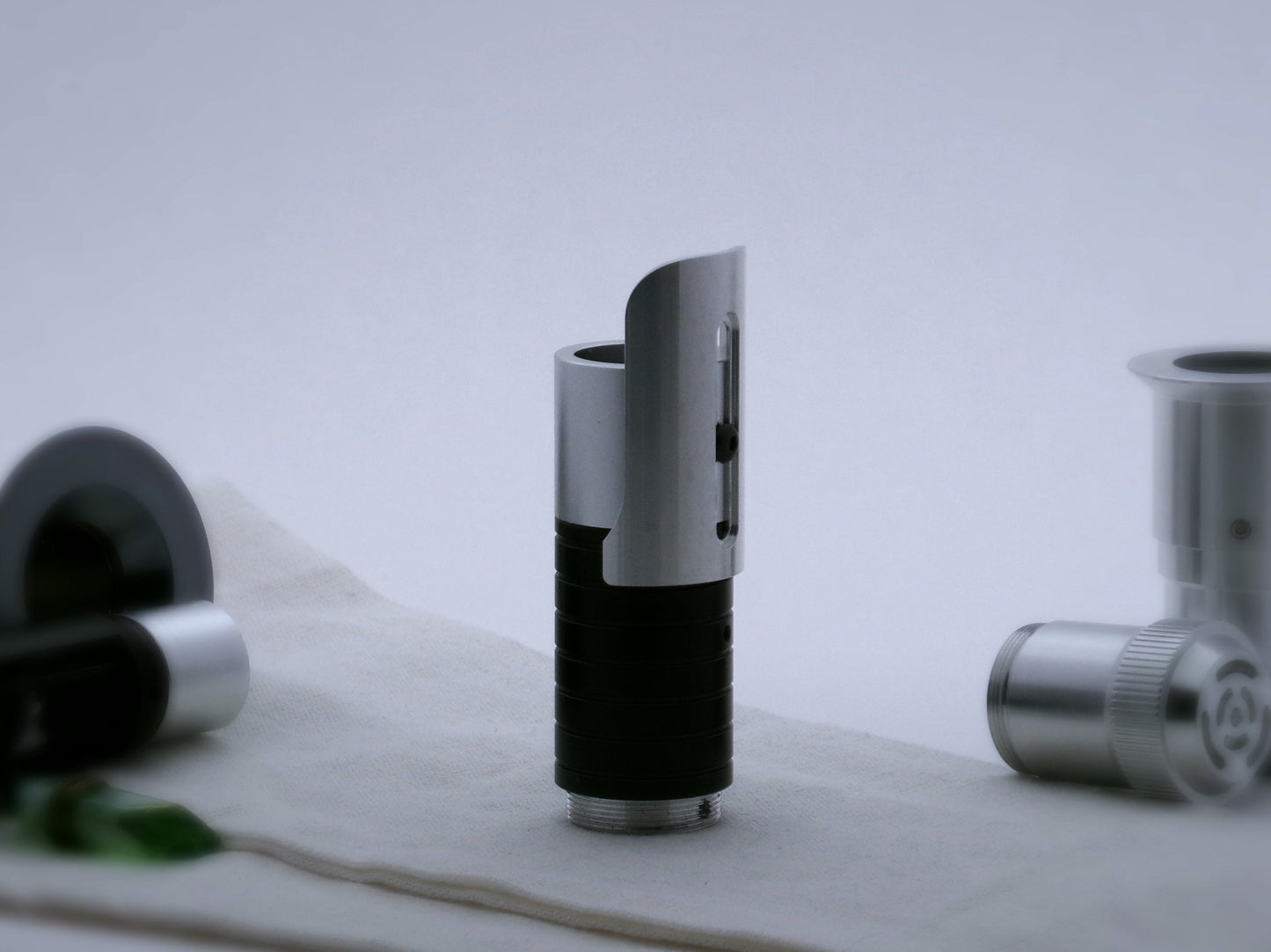 Single, short aluminum half shroud for VHC lightsabers of Sabine Wren design mounted by universal slot to an emitter mock-up; vertical orientation, posterior view.