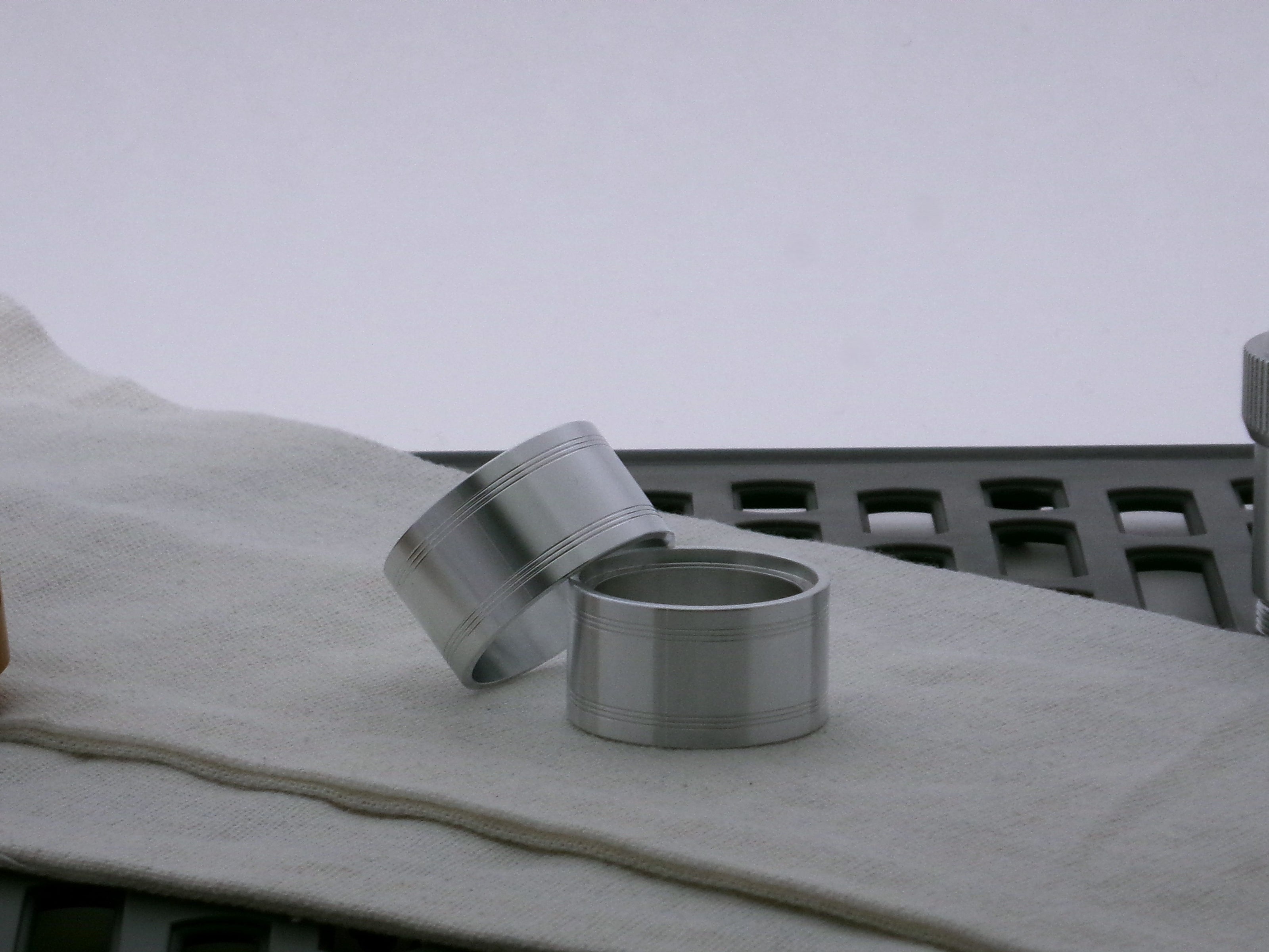 Pair of aluminum accent bands for VHC lightsabers, one askew upon the other, showing a pair of triple band debossed embellishments.