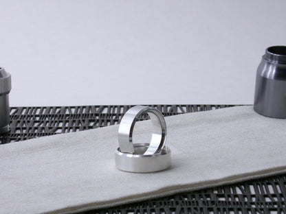 A pair of VHC compatible lightsaber parts, accent bands one supporting the other on cloth.