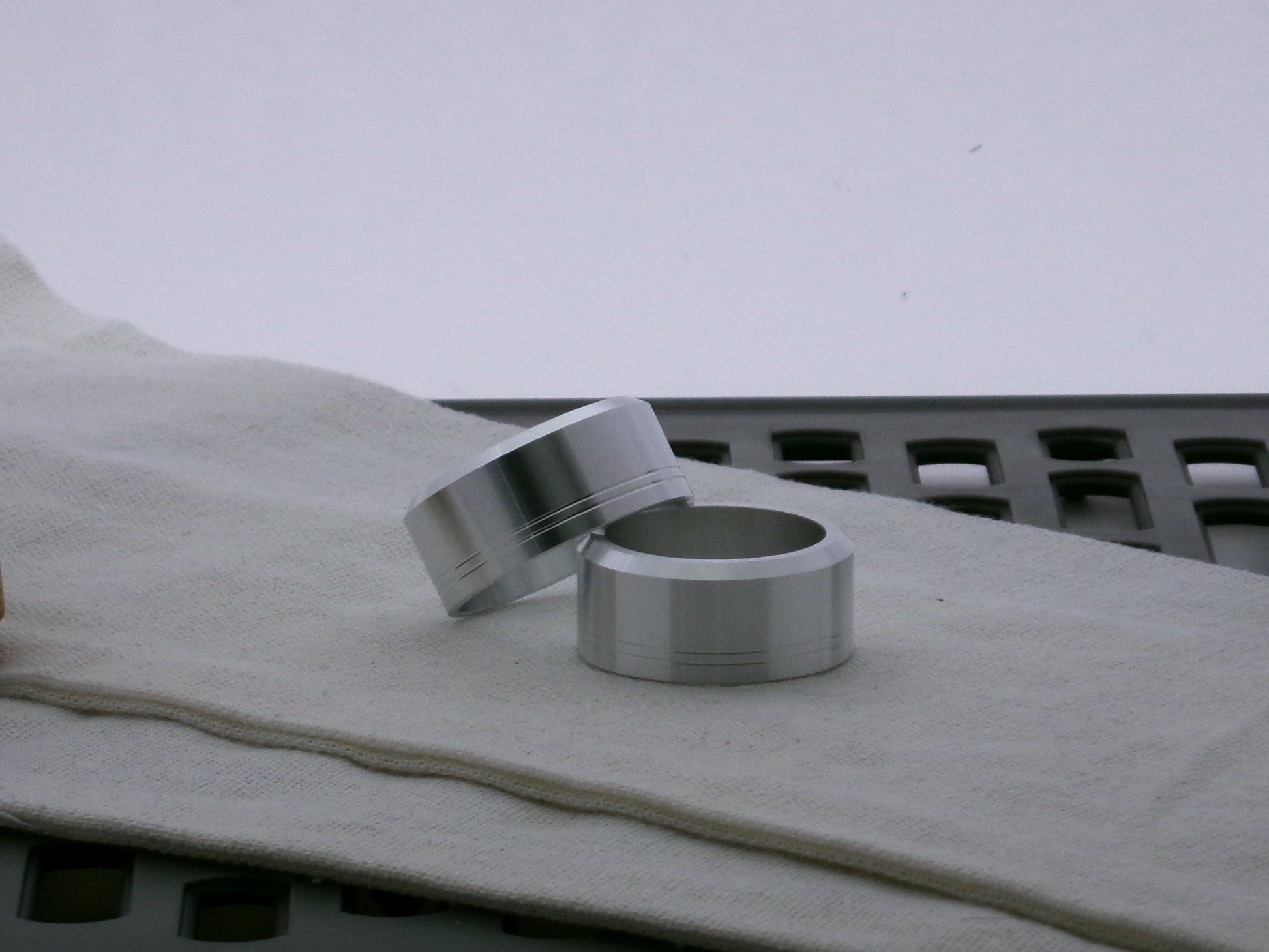 Pair of aluminum accent caps for VHC lightsabers, one askew upon the other, showing depth of bevel and debossed embellishments.