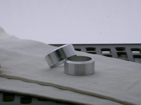 Pair of aluminum accent caps for VHC lightsabers, one askew upon the other, showing depth of bevel and debossed embellishments.