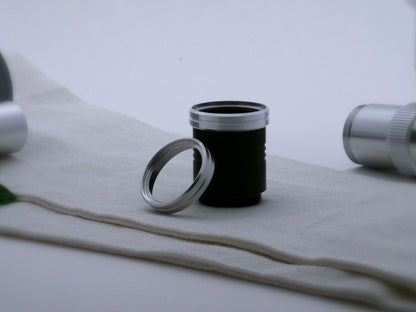 A pair of aluminum accent rings with beveled edges and a central groove for VHC lightsabers, the first installed on a black grip extension, the second leaning against it.