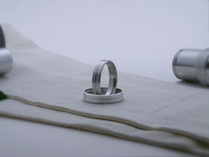 A pair of aluminum accent rings with beveled edges and a central groove for VHC lightsabers; one resting vertical inside the other.