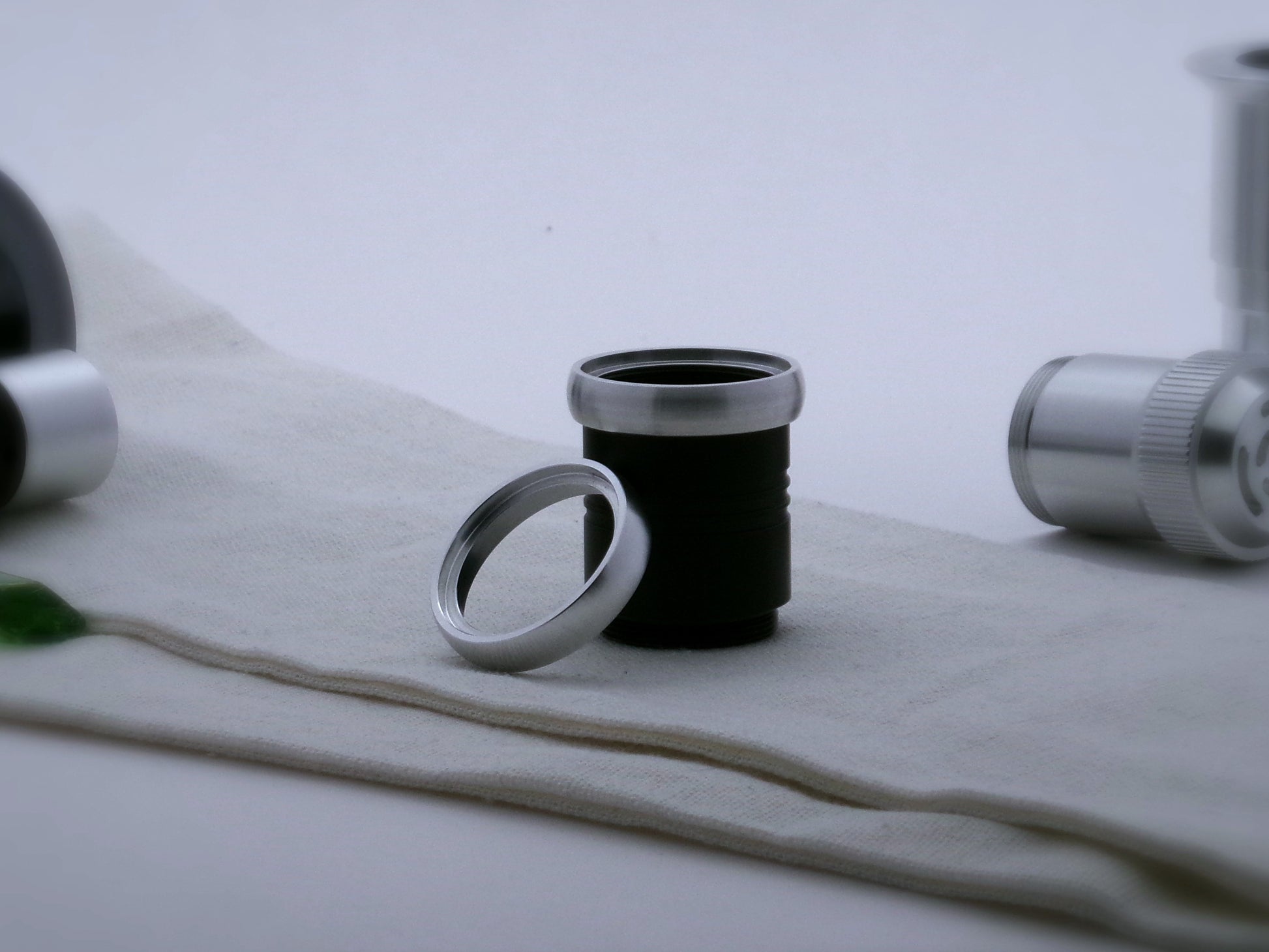 A pair of rounded profile aluminum accent rings for VHC lightsabers, the first installed on a black grip extension, the second leaning against it.