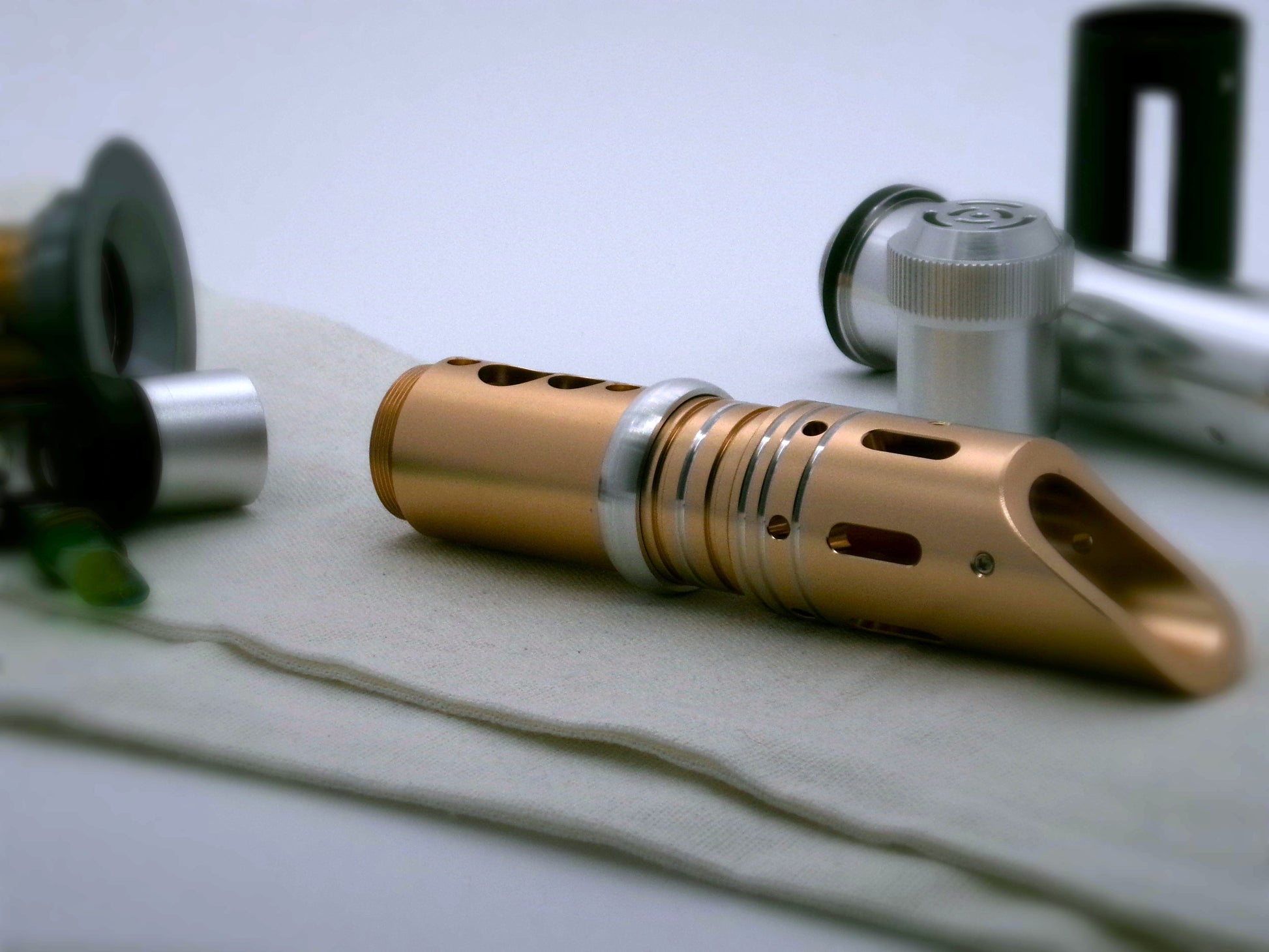 Single, rounded profile, aluminum accent ring installed between the switch and emitter of a golden VHC lightsaber.