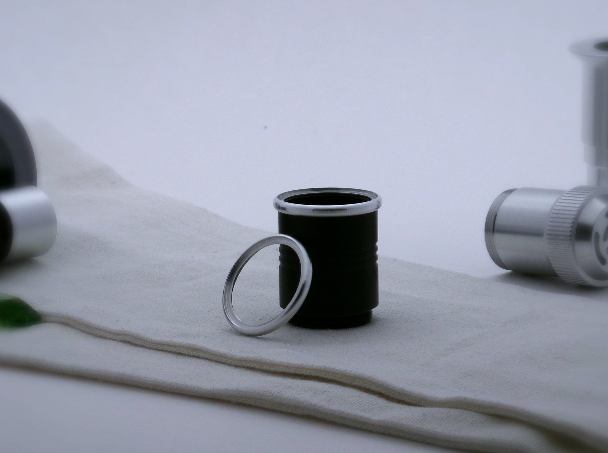 A pair of round profile aluminum accent rings for VHC lightsabers, the first installed on a black grip extension, the second leaning against it.