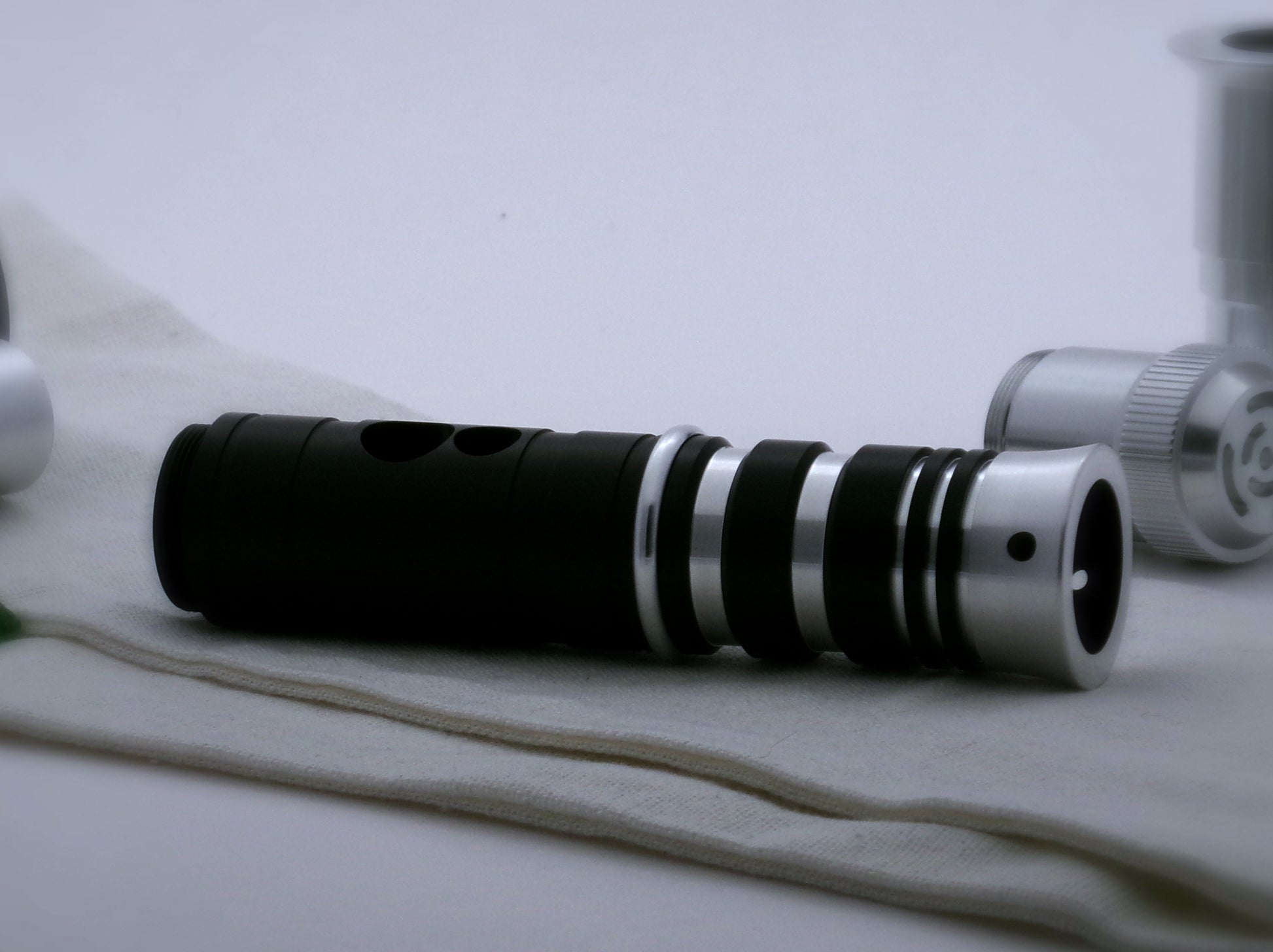 A single, round profile aluminum accent ring installed between a mixed finish emitter and black extension of a VHC lightsaber.