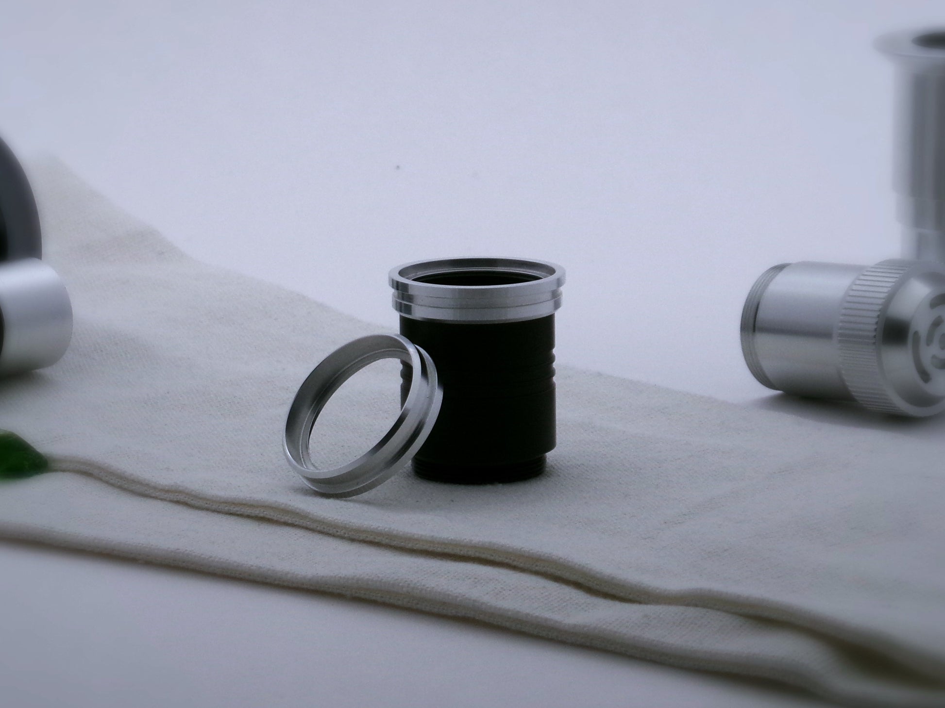A pair of aluminum accent rings for VHC lightsabers with offset bands and deep central groove, the first installed on a black grip extension, the second leaning against it.