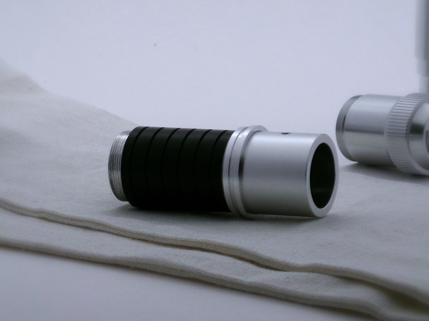Single, aluminum accent ring with offset bands and a deep central groove installed on mixed components of a VHC lightsaber.