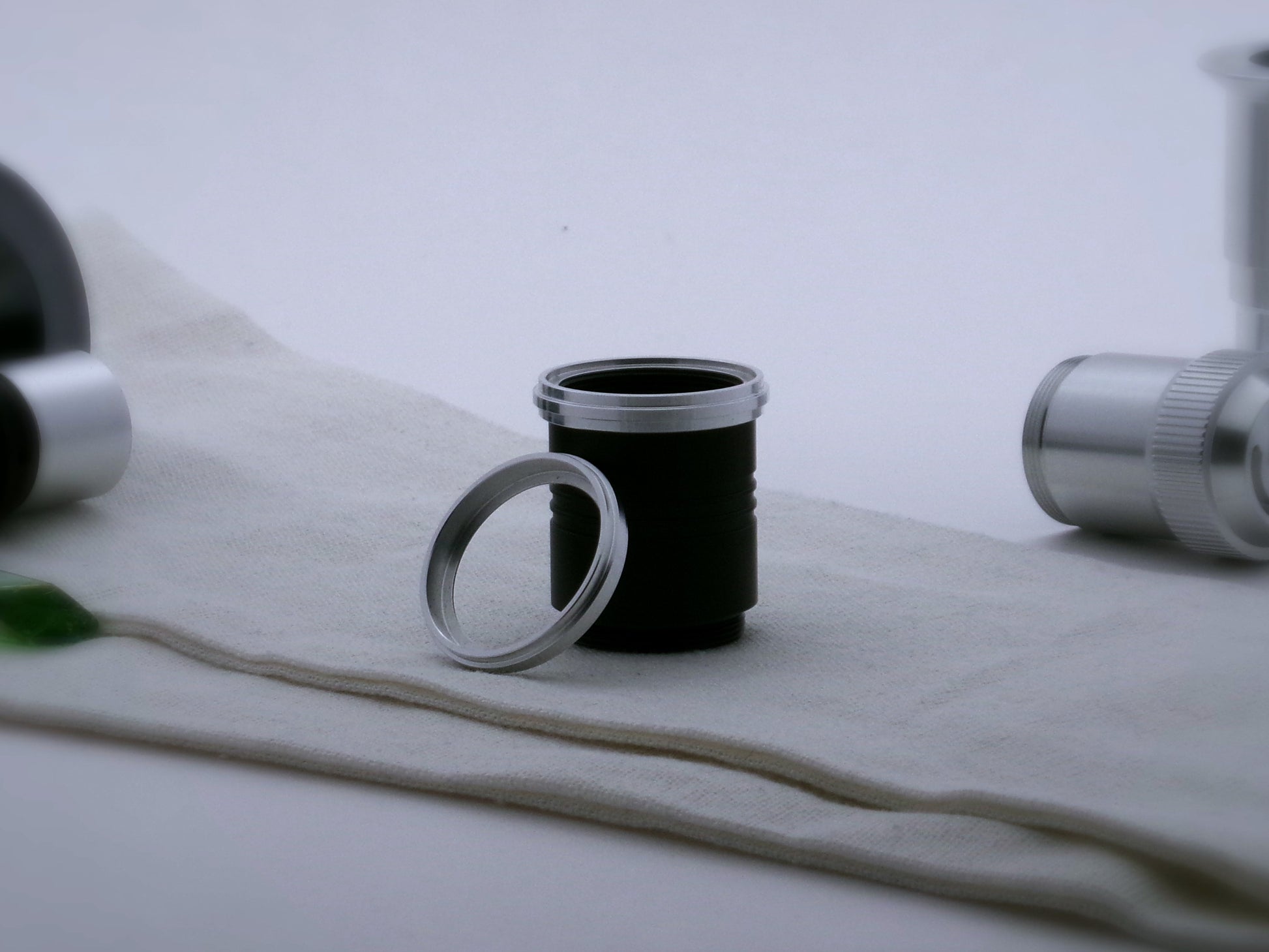 A pair of aluminum accent rings with proud central ribs, the first installed on a black VHC lightsaber grip extension, the second leaning against it.