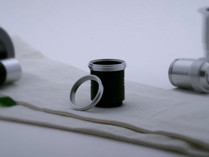 A pair of aluminum accent rings with proud central ribs, the first installed on a black VHC lightsaber grip extension, the second leaning against it.
