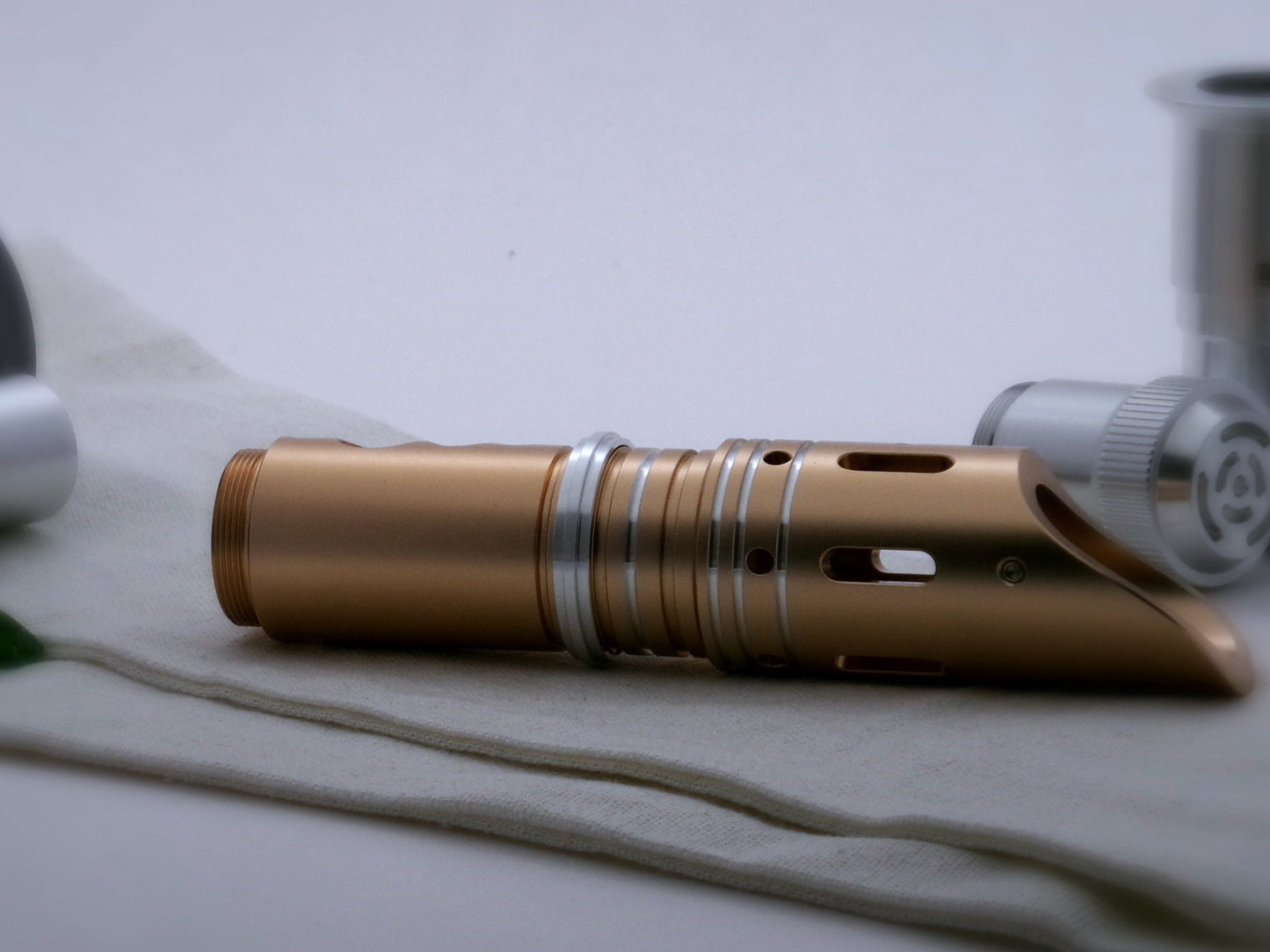 Single, aluminum accent ring with a proud central rib installed between the switch and emitter of a golden VHC lightsaber.