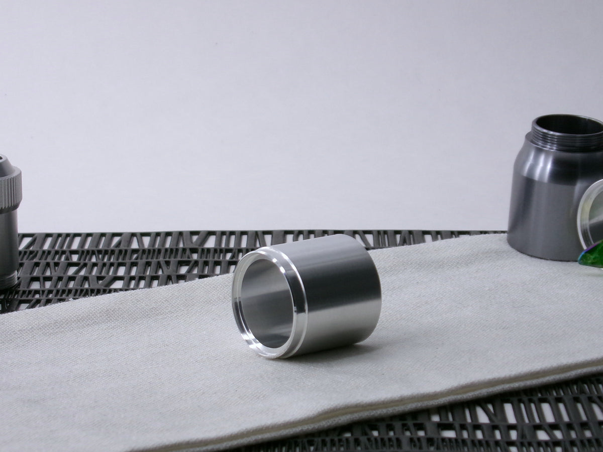 A stepped, VHC-compatible, lightsaber Accent Sleeve sits 3/4 view showing shim-sert, on a cloth.