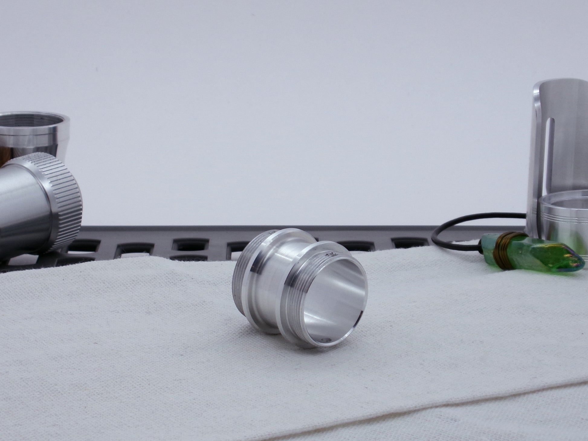 Male threaded adapter for VHC lightsabers resting on cloth, three-quarter view angled right.