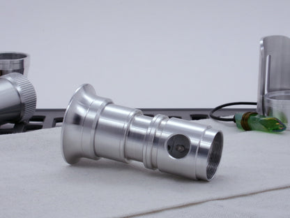 Male threaded adapter for VHC lightsabers installed as part of an Emitter Assembly, all resting on cloth in three-quarter view angled right.