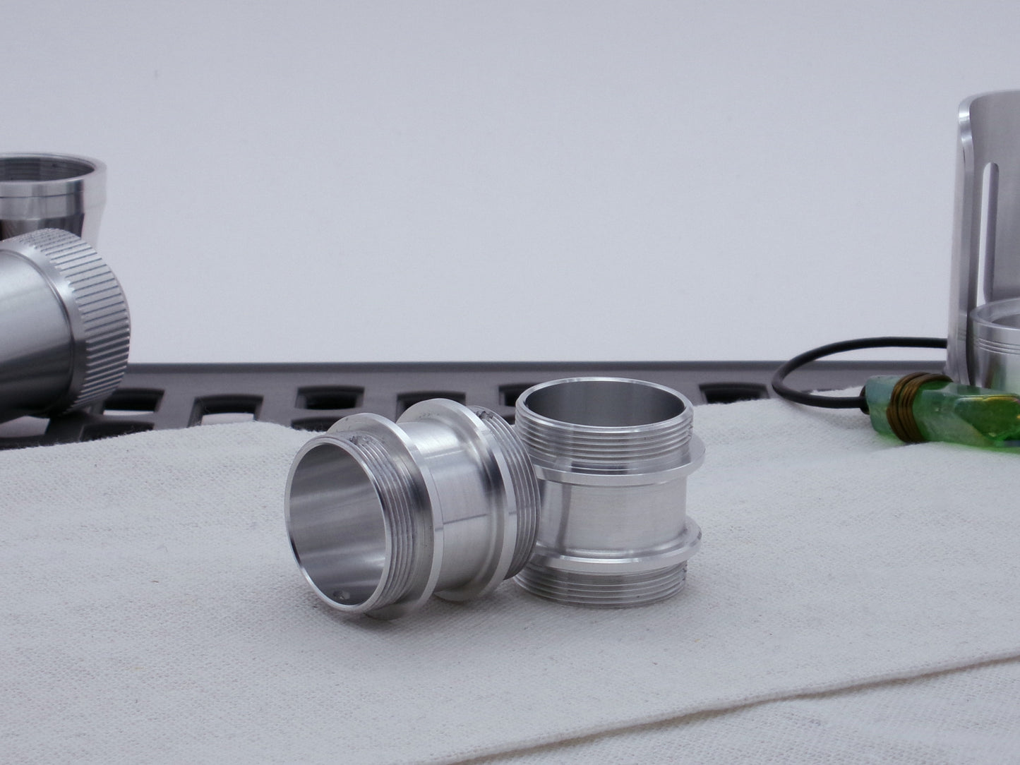 Pair of male threaded adapters for VHC lightsabers resting askew on cloth.