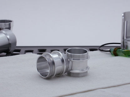 Pair of male threaded adapters for VHC lightsabers resting askew on cloth.