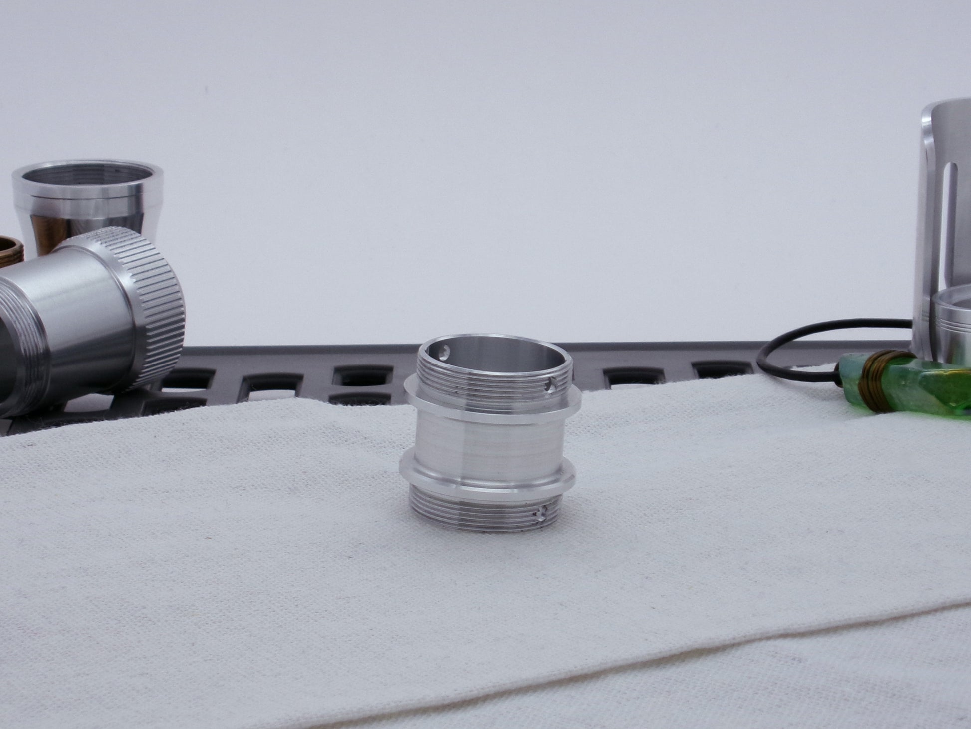 Male threaded adapter for VHC lightsabers resting vertically on cloth.