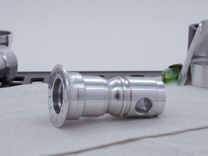 Male threaded, round choke for VHC lightsabers installed as part of an emitter assembly.  Resting on cloth, three-quarter view angled left.