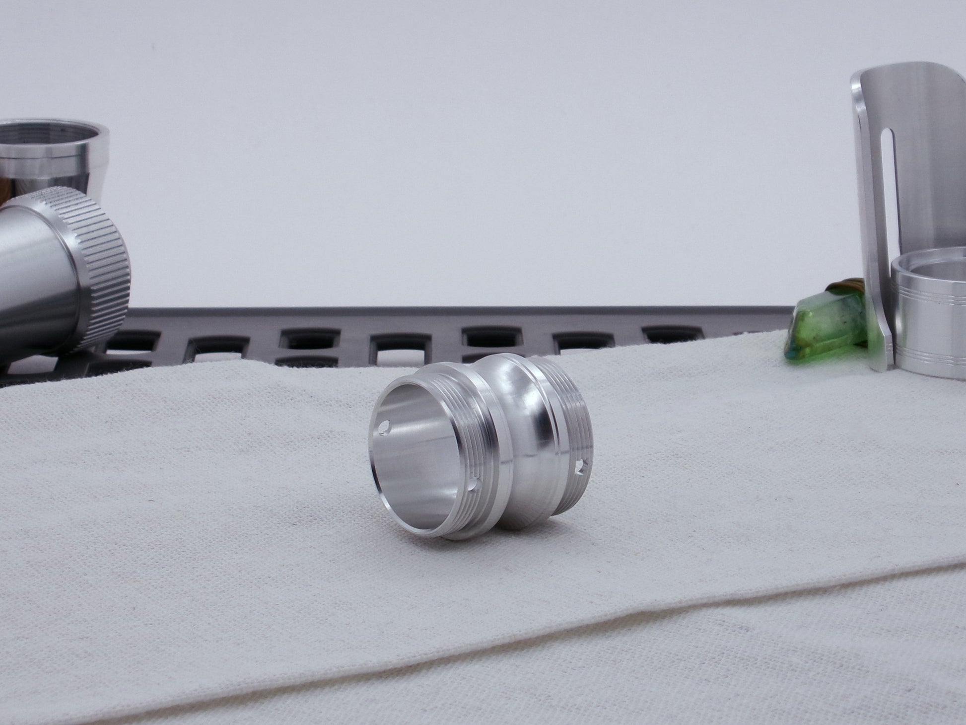 Male threaded, round choke adapter for VHC lightsabers, resting on cloth, three-quarter view.