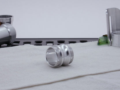 Male threaded, round choke adapter for VHC lightsabers, resting on cloth, three-quarter view.