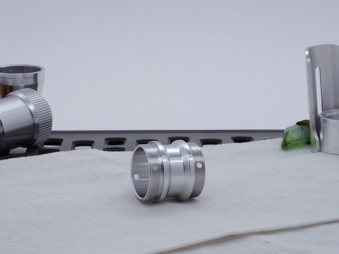 Male threaded, angled choke adapter for VHC lightsabers resting on cloth, three-quarter view angled left.