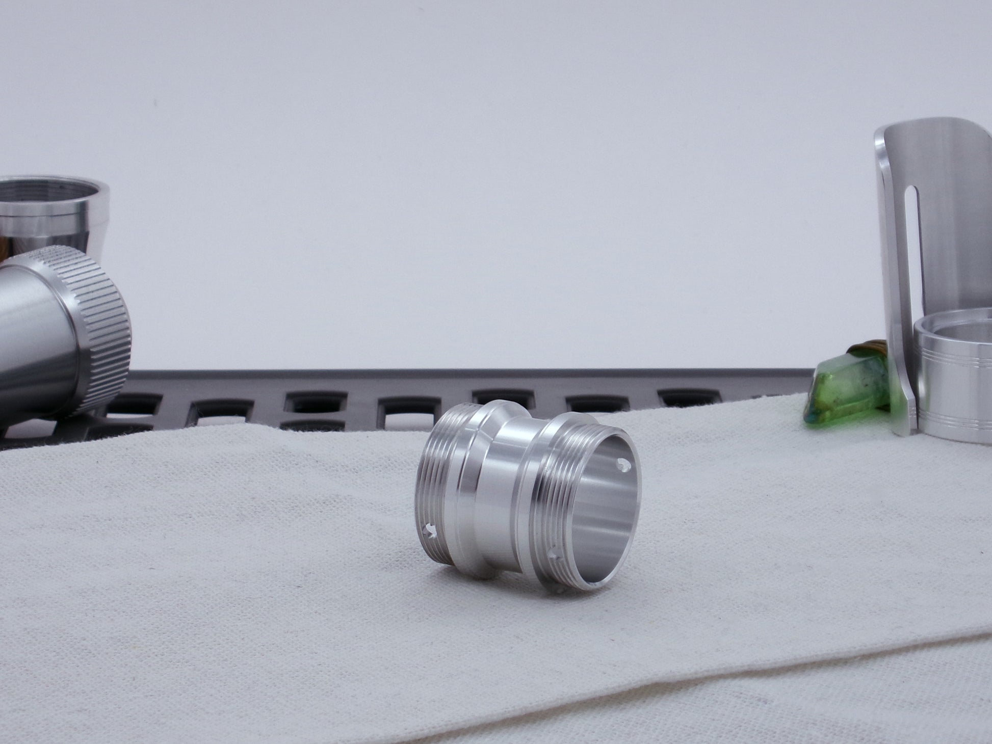 Male threaded angled choke adapter for VHC lightsabers resting on cloth, three-quarter view angled right.