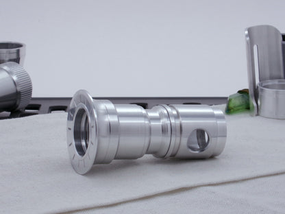 Male threaded, angled choke adapter installed as part of an emitter assembly.  Resting on cloth, three-quarter view angled left.