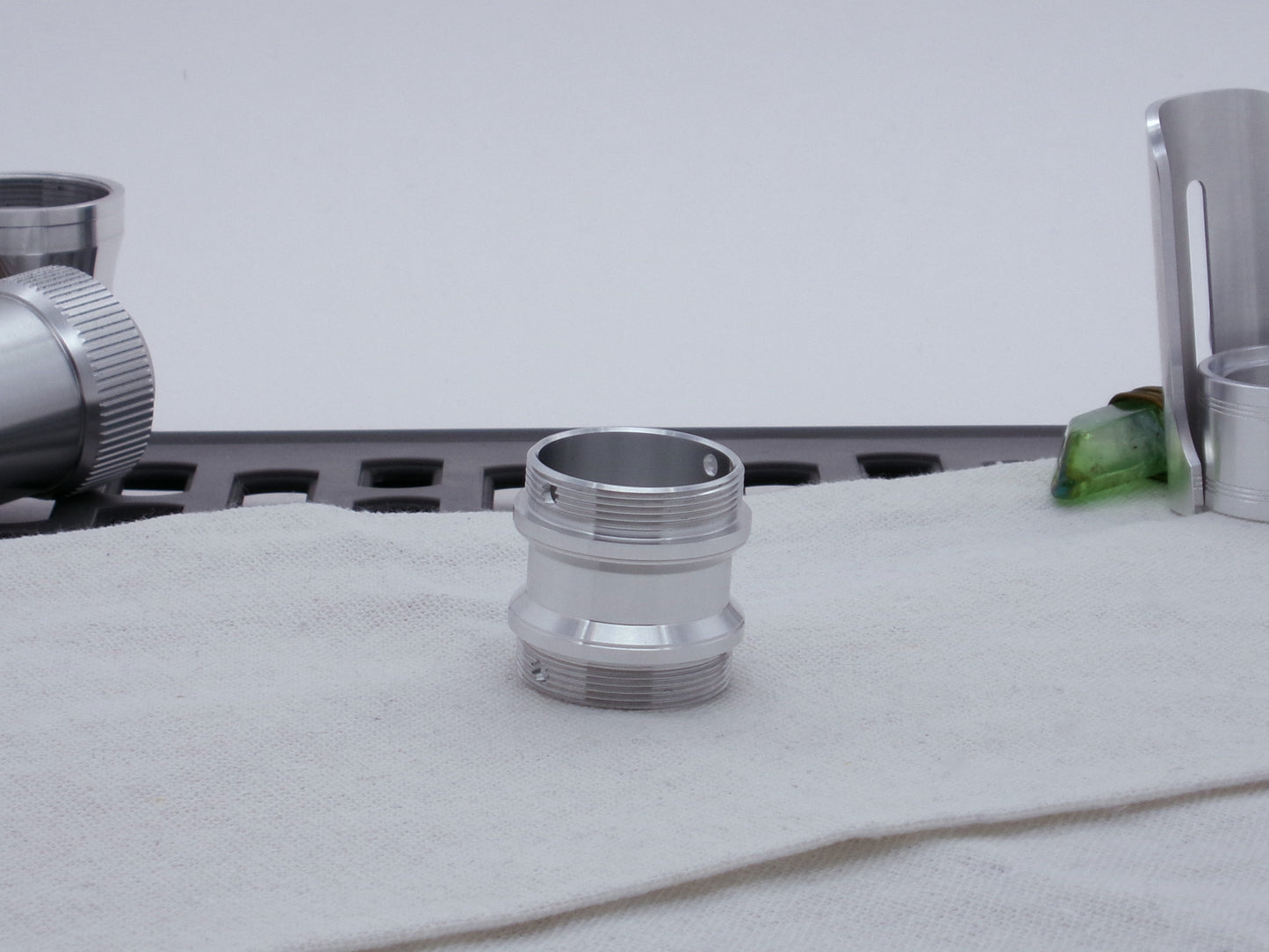 Male threaded adapter for VHC lightsabers sitting vertical on cloth.