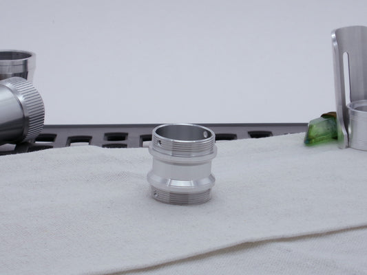 Male threaded adapter for VHC lightsabers sitting vertical on cloth.