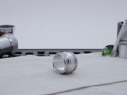 Ki Adi Mundi styled, stepped, male threaded adapter for VHC lightsabers resting on cloth, three-quarter view among other saber parts.