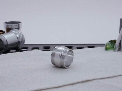 Ki Adi Mundi styled, stepped, male threaded adapter for VHC lightsabers resting three-quarter view angled right on cloth among other saber parts