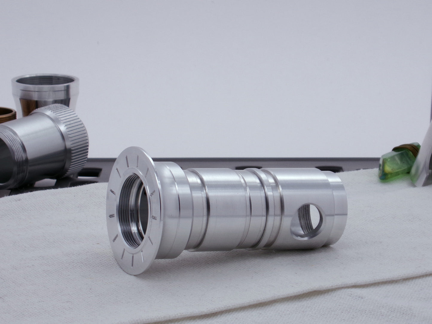 Pair of Ki Adi Mundi styled, stepped male adapters installed as part of an emitter assembly.  Resting on cloth in three-quarter view angled left.