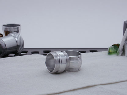 Ki Adi Mundi styled pair of stepped, male threaded adapters for VHC lightsabers, resting askew on cloth among other lightsaber parts.