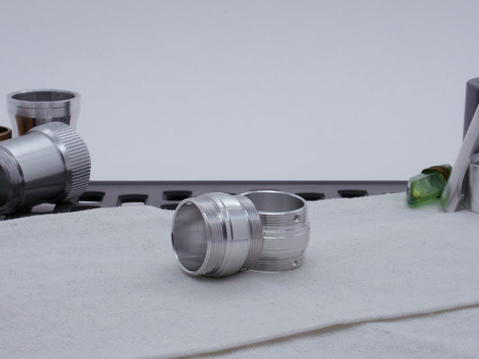 Ki Adi Mundi styled pair of stepped, male threaded adapters for VHC lightsabers, resting askew on cloth among other lightsaber parts.