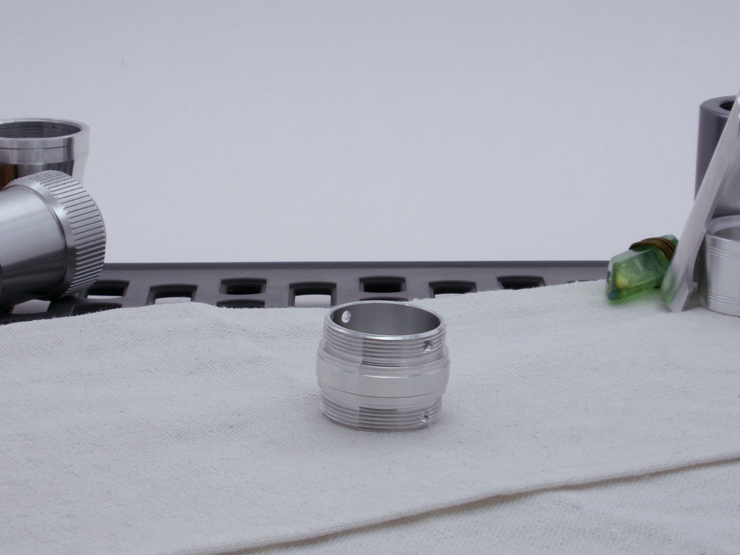 Ki Adi Mundi styled, male threaded, stepped adapter, for VHC lightsabers resting vertically on cloth among other saber parts.