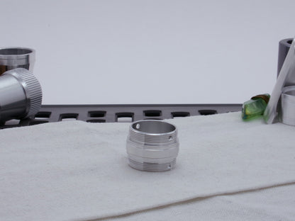 Ki Adi Mundi styled, male threaded, stepped adapter, for VHC lightsabers resting vertically on cloth among other saber parts.