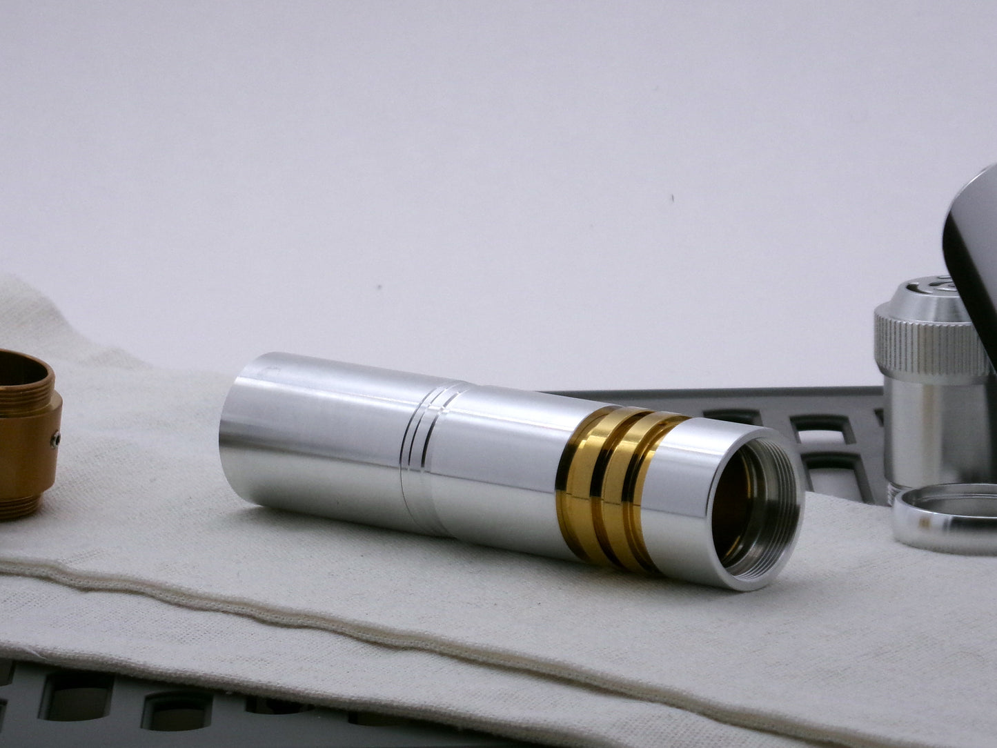 Single aluminum female/female threaded body component installed on a golden ribbed VHC lightsaber component; three-quarter view.