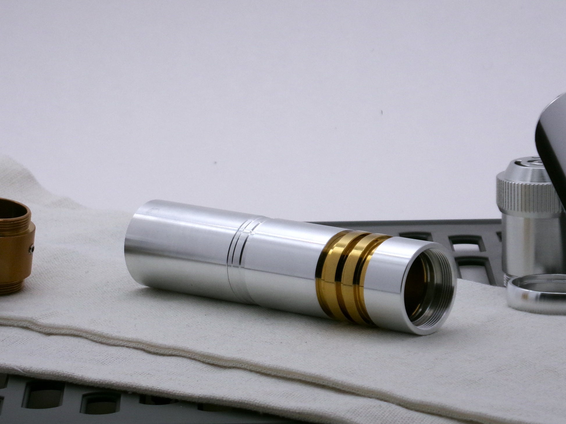 Single aluminum female/female threaded body component installed on a golden ribbed VHC lightsaber component; three-quarter view.