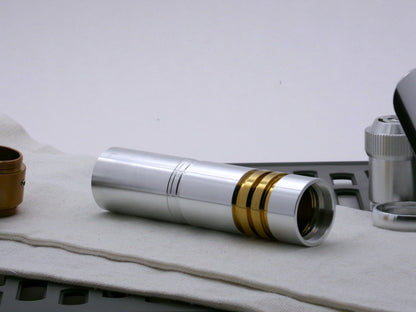Single aluminum female/female threaded body component installed on a golden ribbed VHC lightsaber component; three-quarter view.