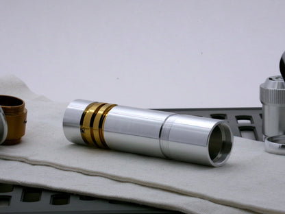 Single aluminum female/female threaded body component installed atop a golden VHC lightsaber component; three-quarter view.