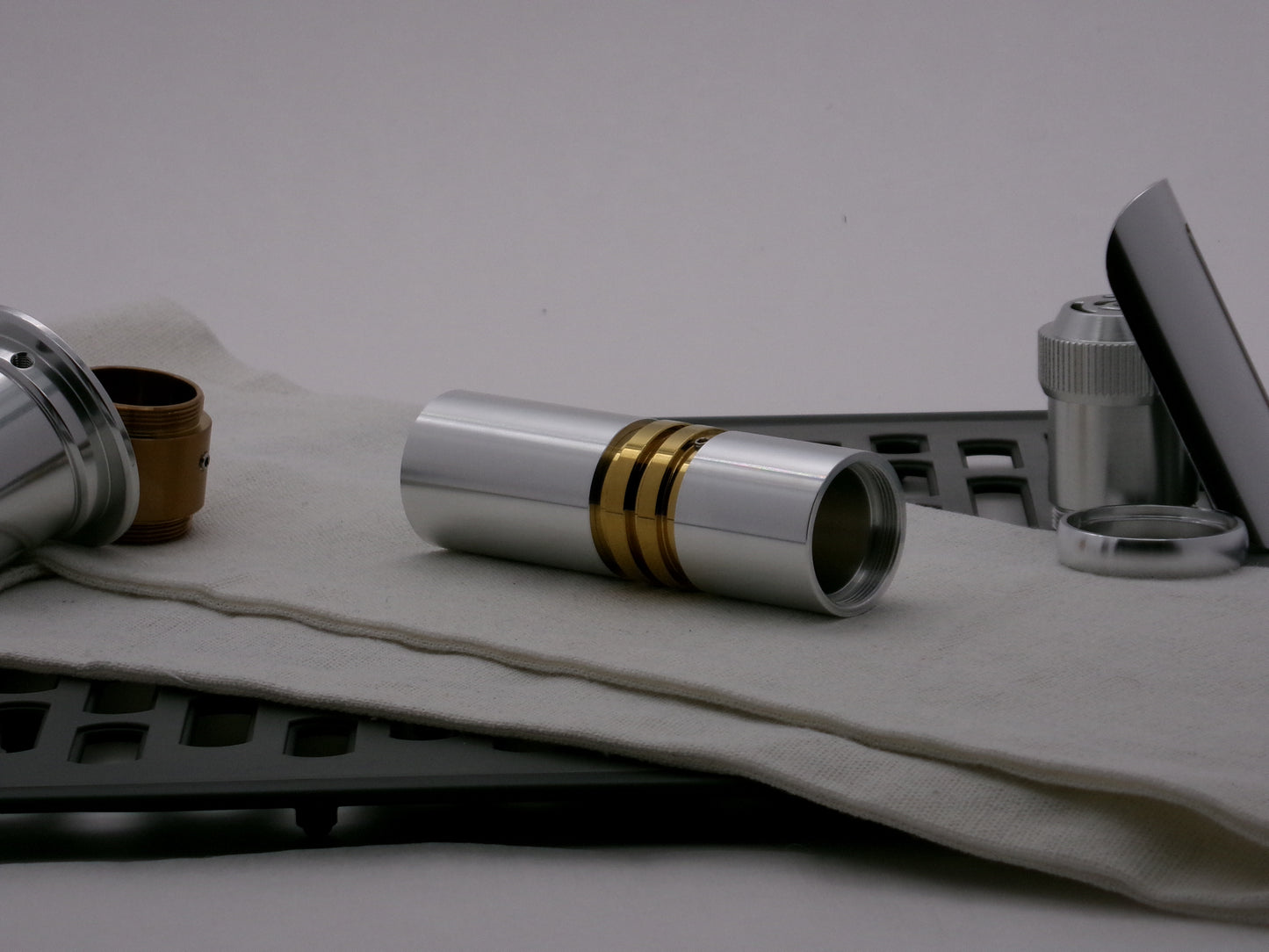 Single aluminum female/female threaded body component installed below a golden ribbed VHC lightsaber component; three-quarter view.